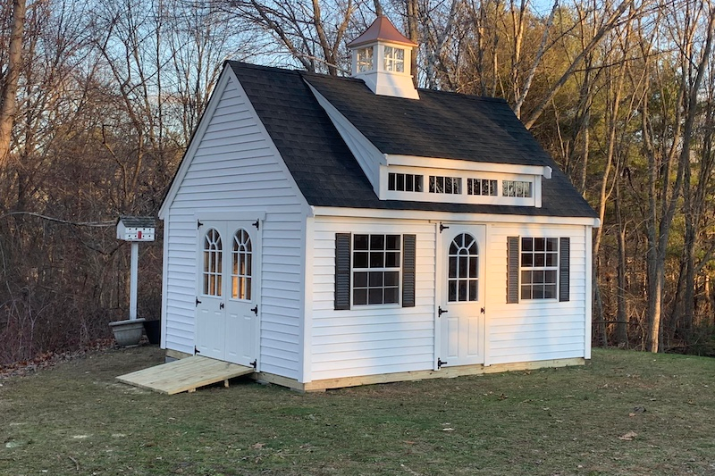 beautiful white and black shed with a loft, front door, back garage door with a ramp placed in a yard