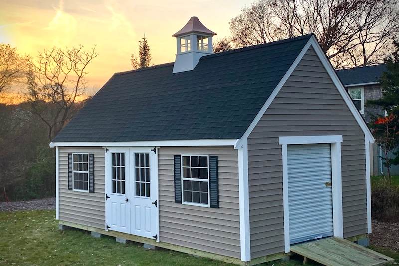 harmonizing home design with a matching shed - custom shed options and features, beige and white shed with windows, shutters, double doors, a side access garage door, black roof