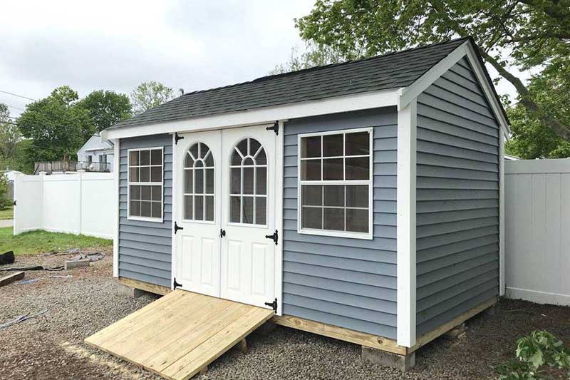 small backyard sheds make a big difference for storage and organization - blue gray shed with white double doors, a ramp, and two windows