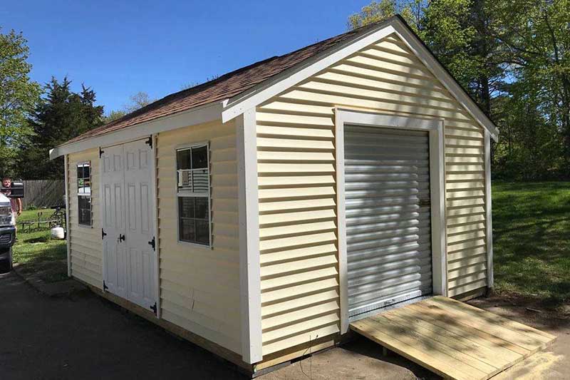 yellow shed with a reddish brown room, a garage door with a ramp, double french doors and a window