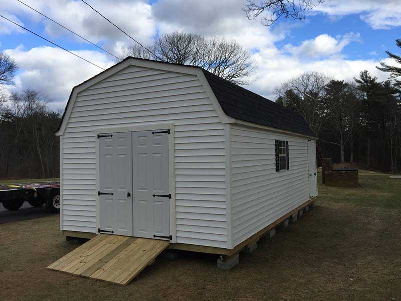large custom sheds with double doors - this one features a double-door garage with a ramp and a standard regular door