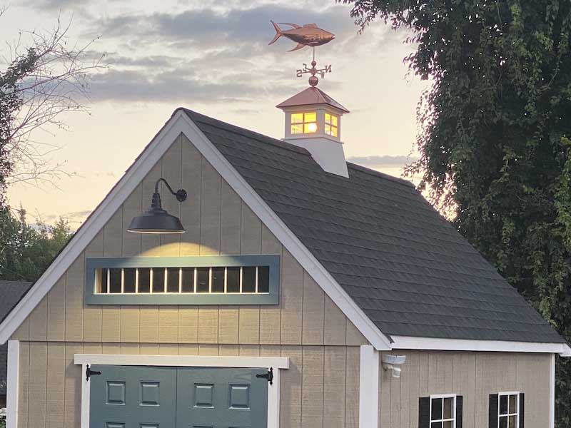 small backyard shed with lots of custom features, including decorative roofing, lighting, and more